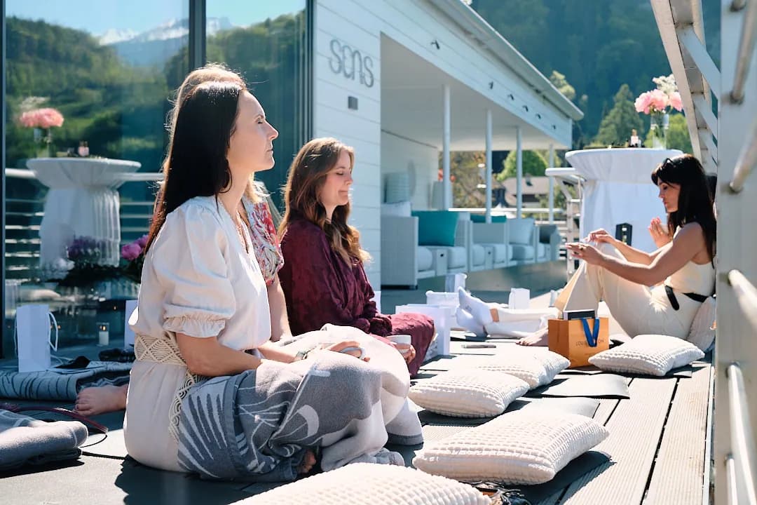 Frauen sitzen auf Kissen auf der Seeterrasse und hören zu
