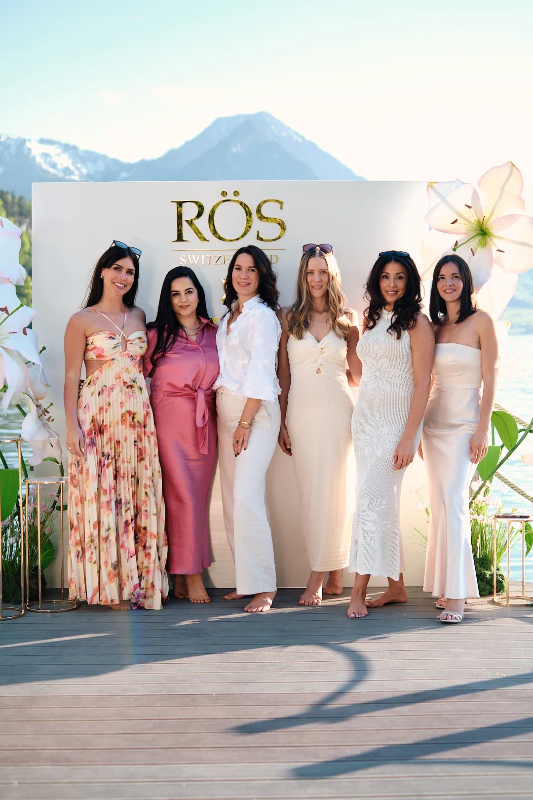 Sechs Frauen in eleganten Kleidern posieren für ein Gruppenfoto