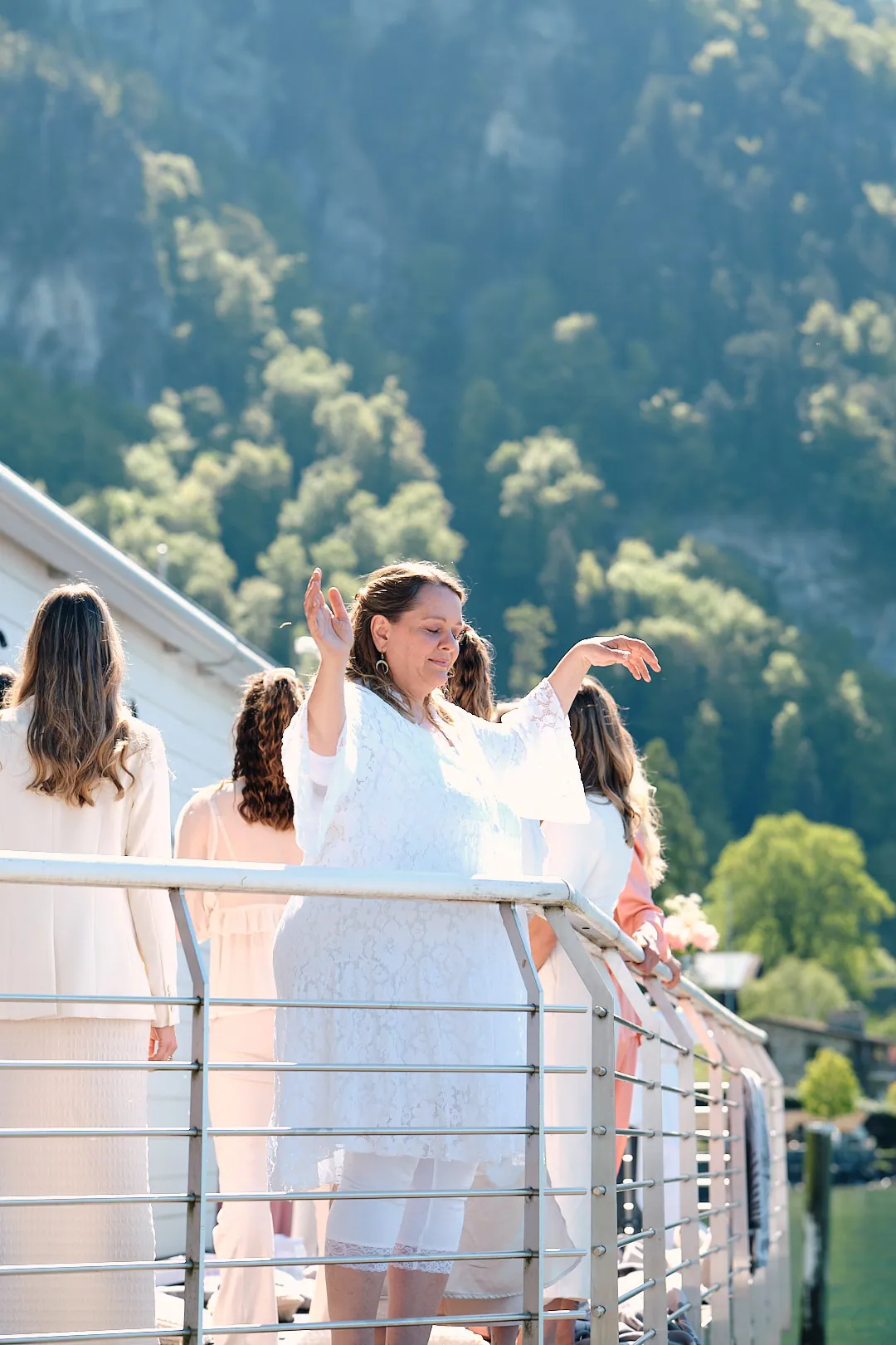 Frauen tanzen mit offenen Armen auf der Terrasse über dem See